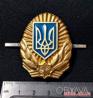 Кокарда з золотистим тризубом у синьому щиті